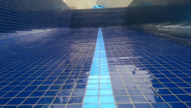 Blue mosaic tiles being laid in residential pool